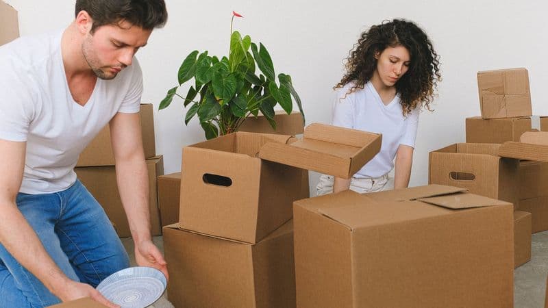 A couple packing boxes as they move into their new home