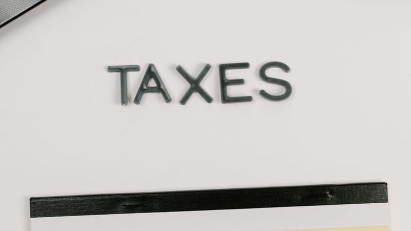 A desk with a calculator, notepad and TAXES lettering for end-of-financial-year planning